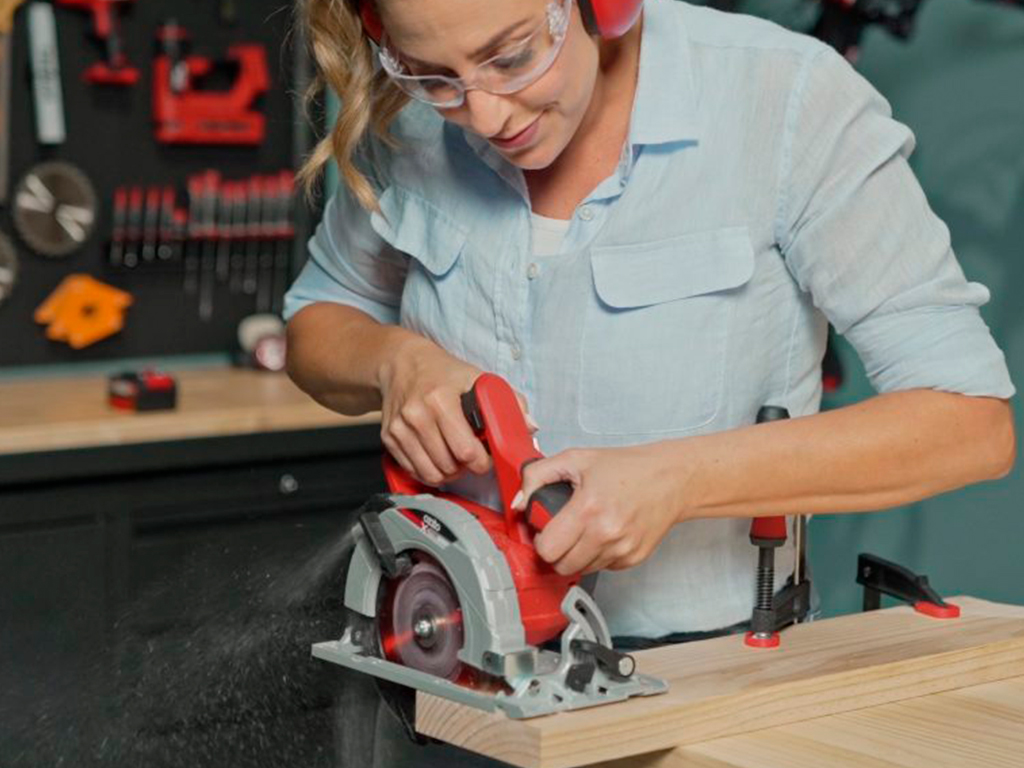 A woman is working with a cordless hand circular saw