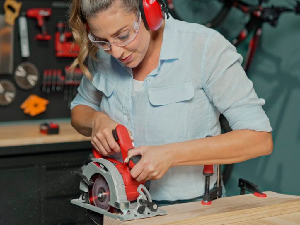 A woman is working with a cordless hand circular saw