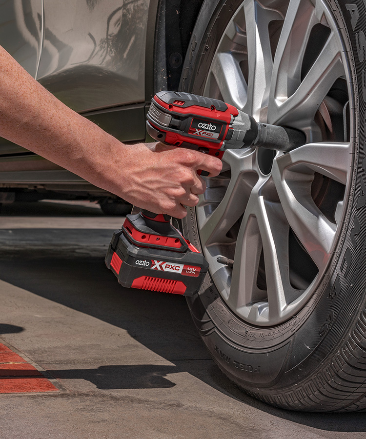 A man is change his car wheels a with a impact wrench