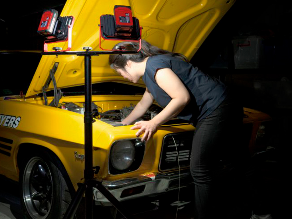 A woman working on her car with a pxc lamp