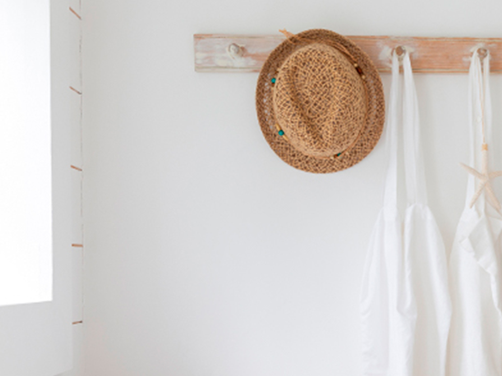 Several coat hooks with towel and straw hat